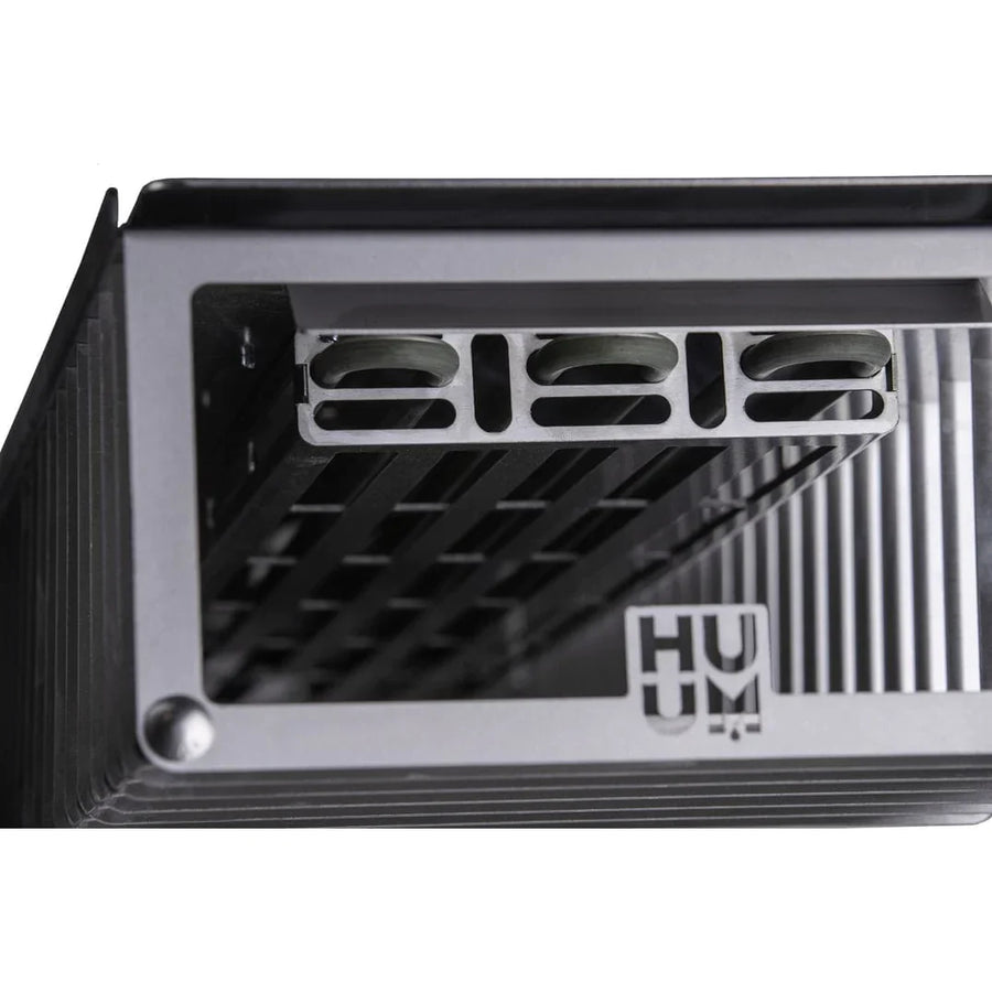 Close-up of a metallic grid-structured object with vent openings and the HUUM logo on a ribbed surface, showcasing industrial design similar to the HUUM CLIFF Mini Series 4kW Sauna Heater Package.