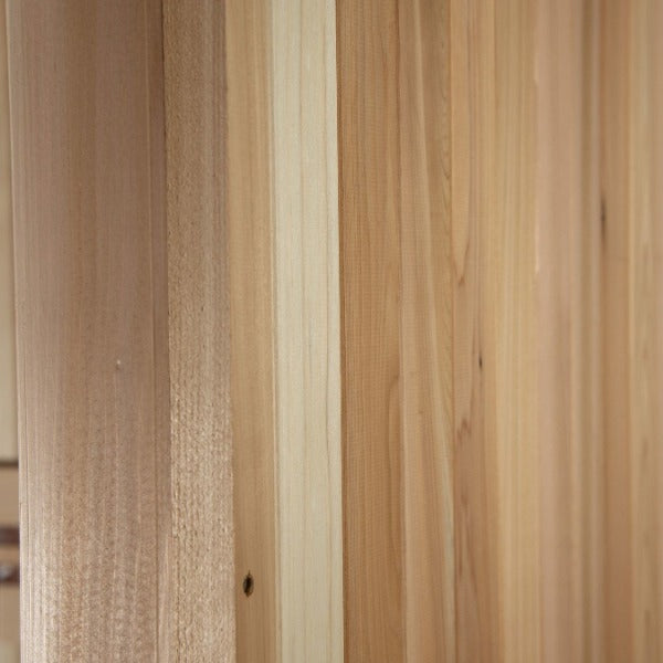 Close-up of vertical wooden planks in the Almost Heaven Denali 6 Person Indoor Sauna, showcasing natural grain patterns and textures in light brown and beige tones.