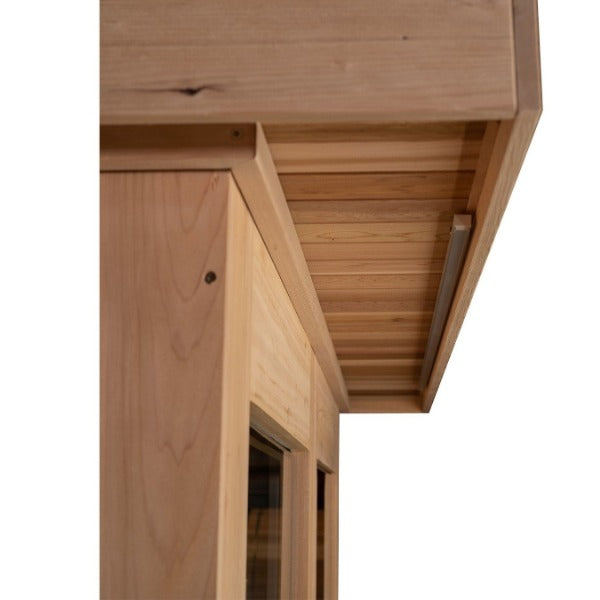 Close-up of the Almost Heaven Denali 6 Person Indoor Sauna’s corner roof and upper wall, showing natural wood grain, a small overhang with horizontal panels, and a window below.