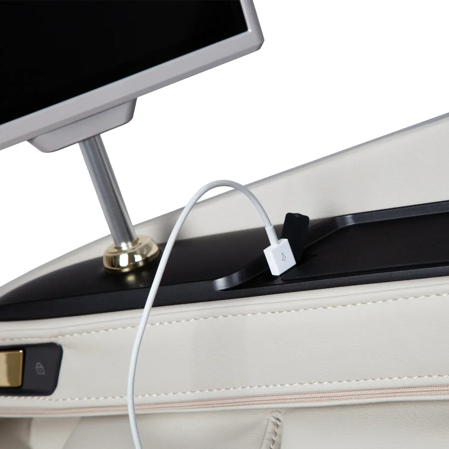 A close-up of the Osaki Grand Duo 4D+4D Massage Chair by Osaki shows its white charging hub with a connected USB cable, placed on beige leather near a monitor and an AI health sensor lock button.