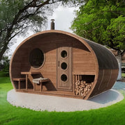 The SaunaLife Model G11 Outdoor 8 Person Sauna by SaunaLife features a small, round design with a circular window, a door with three round windows, outdoor bench, and firewood stack on white gravel among grass and trees.