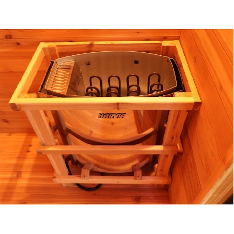 The SunRay Denali 4-Person Contemporary Outdoor Sauna features a wooden heater with a metal element and protective frame, placed in the corner of its red cedar room. The SunRay-branded heater ensures warmth for your group sauna sessions.