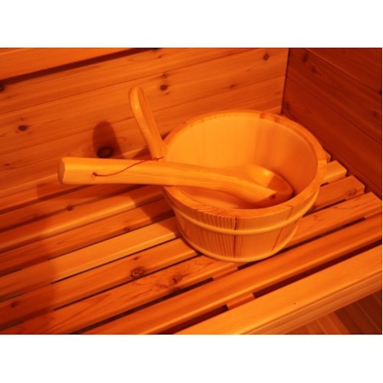 A SunRay Denali 4-Person Contemporary Outdoor Sauna features a wooden sauna bucket with a ladle on a bench, all set against the warm wooden paneling of this premium SunRay outdoor sauna.