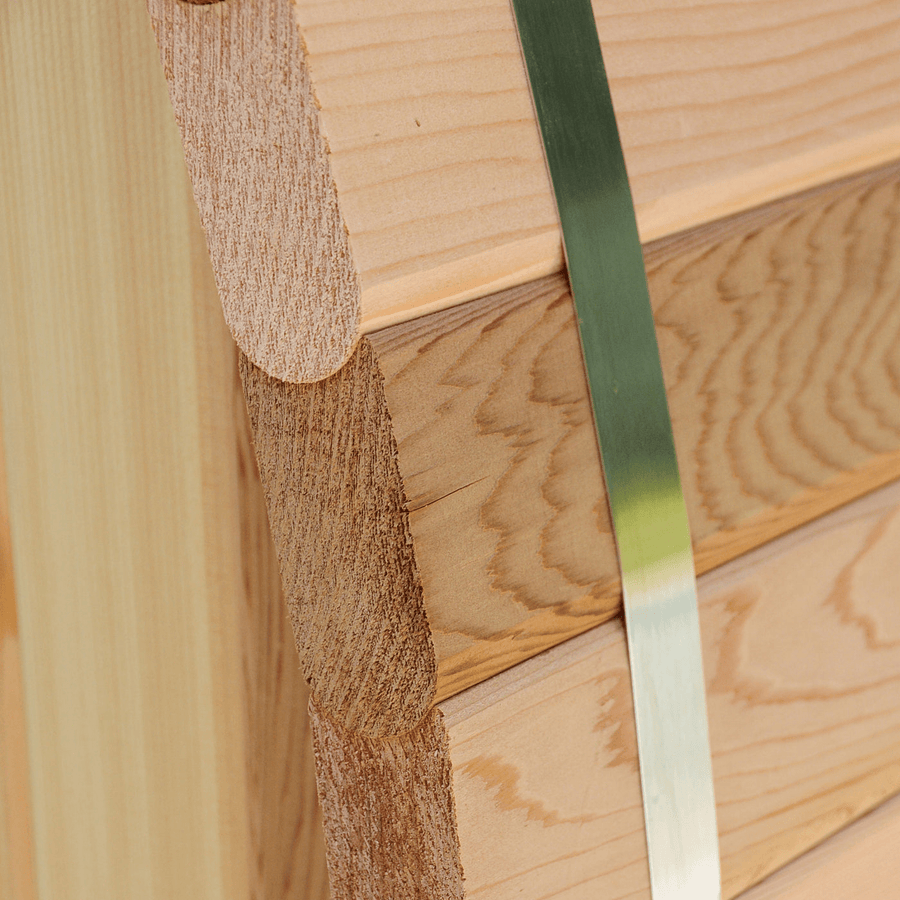Close-up of finely crafted wooden planks with rounded edges, secured by a metal strap—premium quality for the Almost Heaven Grandview 4-6 Person Canopy Barrel Sauna. The wood grain highlights craftsmanship from the trusted Almost Heaven brand.