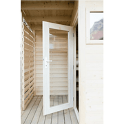 An open white wooden framed glass door leads from a light wood building to the Almost Heaven Timberline 6 Person Cabin Sauna on a semi-enclosed patio. The pale wood walls and ceiling feature a window on one side. Brand: Almost Heaven.