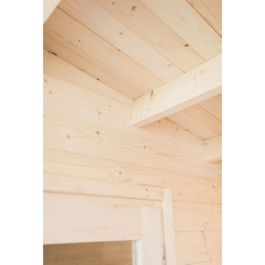 Interior view of light wood ceiling and wall corner with panels and beams, above a door frame—showcasing natural grain and knots found in the Almost Heaven Timberline 6 Person Cabin Sauna.