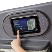 A hand touches a digital control screen on the gray armrest of the Osaki Flagship Duo Massage Chair, displaying advanced AI massage options and adjustable intensity and duration settings.