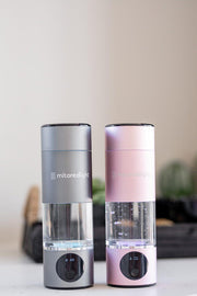 Two MitoHYDRO™ Ultra Premium Hydrogen Water Bottles by Mito Red Light, one gray and one pink, sit side by side. Each features a clear chamber, digital display at the base, and produces antioxidant-rich hydrogen water.