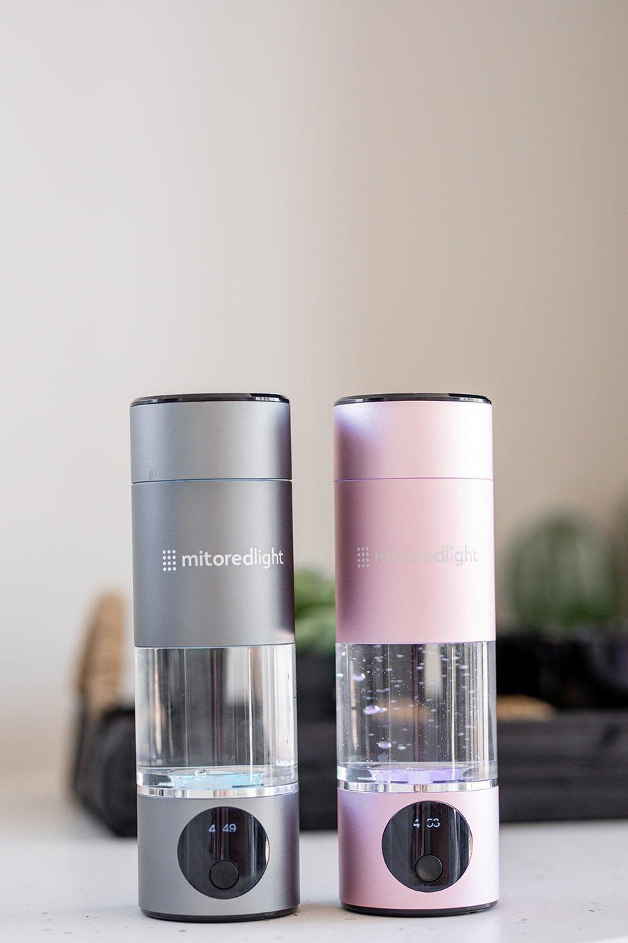 Two MitoHYDRO™ Ultra Premium Hydrogen Water Bottles by Mito Red Light, one gray and one pink, sit side by side. Each features a clear chamber, digital display at the base, and produces antioxidant-rich hydrogen water.