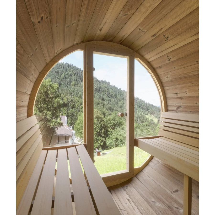 The SaunaLife Model E8 6 Person Barrel Sauna features an ergonomic interior with benches on both sides and a glass door showcasing scenic views of green trees and forested hills.