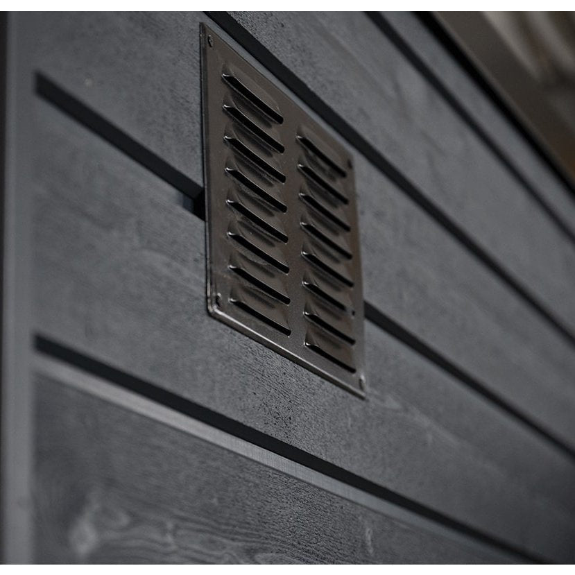 A close-up of a rectangular metal vent with slats on the dark grey wood exterior of the SaunaLife G6 5-Person Outdoor Cabin Sauna, enhancing ventilation and style for this luxurious SaunaLife sauna.
