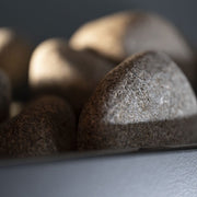 Close-up of smooth, rounded gray stones in the SaunaLife G6 5-Person Outdoor Cabin Sauna, their textured surfaces highlighted by sunlight—showcasing how SaunaLife uses natural elements to enhance relaxation.