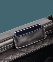 A close-up of a dark quilted leather bag with a slim dark blue smartphone in its pocket, evoking the space-saving efficiency seen in modern designs like the Daiwa Legacy 4 Massage Chair by Daiwa.