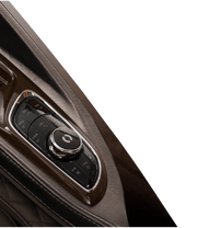 Close-up of the Daiwa Supreme Hybrid Massage Chair’s center console, featuring a glossy rotary dial with control buttons, set in brown wood or metallic trim with quilted leather upholstery, echoing the brand's signature blend of luxury and comfort.