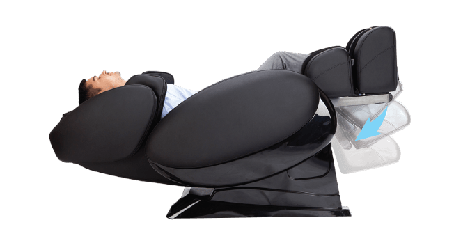 A person relaxes in the Daiwa Supreme Hybrid Massage Chair by Daiwa, featuring a modern black design and an L-shaped massage track, with raised legs for support while enjoying a soothing massage.