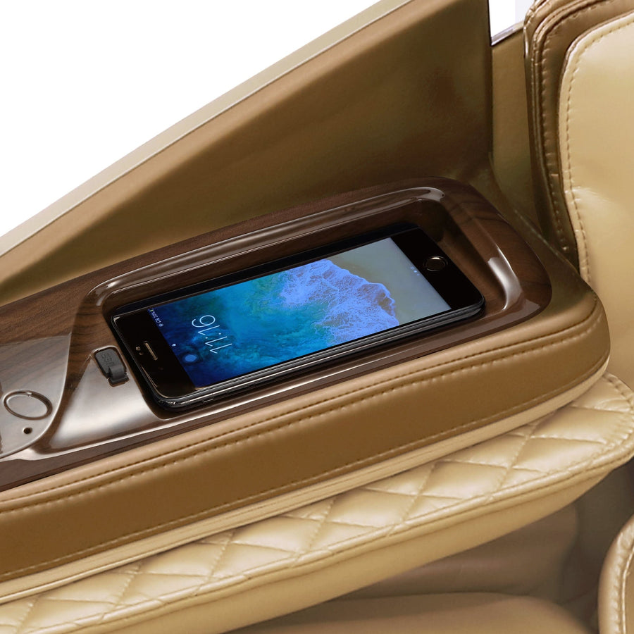 A smartphone sits in a built-in holder on the tan leather armrest of the Daiwa Supreme Hybrid Massage Chair, featuring quilted stitching, elegant wood trim, and an L-shaped massage track for ultimate comfort.
