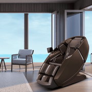 The Daiwa Supreme Hybrid Massage Chair by Daiwa, featuring an L-shaped massage track and modern brown design, sits in a sunlit room with large windows and ocean views, blending comfort with a serene, contemporary setting.
