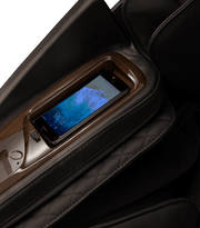A smartphone sits in a built-in holder on the armrest of the Daiwa Supreme Hybrid Massage Chair by Daiwa, with the phone's lock screen partially visible.