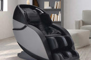 The Kyota Kansha M878 Massage Chair by Kyota, in black and gray, features padded leg, arm, and head supports plus a sleek 4D design—shown in a bright room with wooden floors and a bookshelf behind it.
