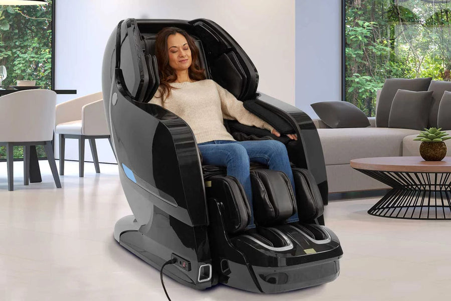 A woman relaxes in a Kyota Yosei M868 4D Massage Chair by Kyota, enjoying a soothing foot massage in a modern living room filled with natural light, lush green plants, and contemporary furniture.