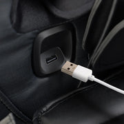 A close-up of a white USB cable being plugged into a black USB port on the Osaki 4D YogaFlex Massage Chair, highlighting its convenient charging feature by Osaki.