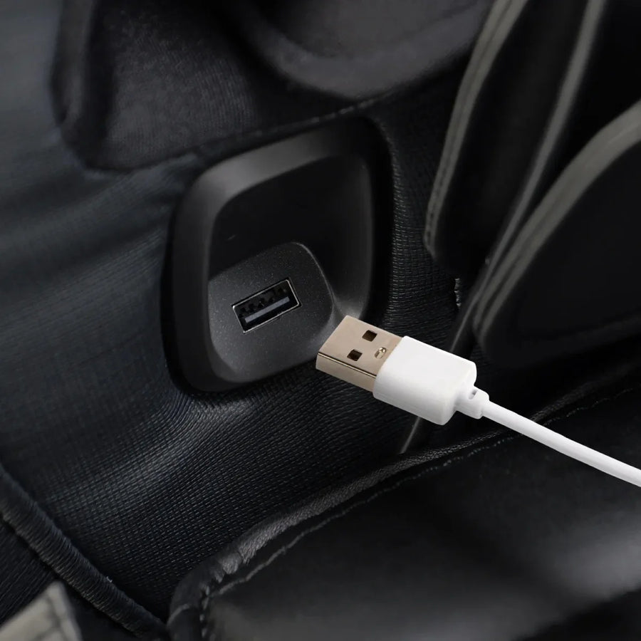 A close-up of a white USB cable being plugged into a black USB port on the Osaki 4D YogaFlex Massage Chair, highlighting its convenient charging feature by Osaki.