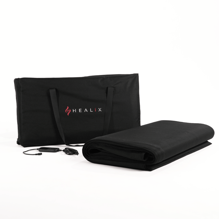 A black HEALiX Infrared carrying case stands upright beside a rolled-up black mat—the HEALiX Glow Pod—with its control remote and power cord displayed in front, all set against a white background.