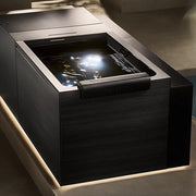 The Kohler x Remedy Place Ice Bath by Kohler features a sleek, modern rectangular design in black, softly lit and filled for hydrotherapy, set against a minimalist backdrop—ideal for relaxation and wellness routines.