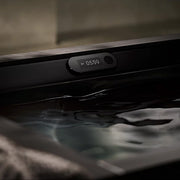 A close-up of the Kohler x Remedy Place Ice Bath digital display by Kohler shows 39°F and a timer at 05:59, with light reflecting off cold water in the tub during cold immersion.