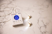 A compact white MitoBOOST™ Intranasal Device System by Mito Red Light, featuring a blue digital screen and earbud-style attachments, rests on marble—designed for sinus health, immune support, and brain health.
