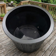 The SaunaLife Model S1BC – 1-Person Immersion Tub with Black Chiller & Heater sits empty on a wooden deck, surrounded by greenery and patio furniture—a perfect outdoor home spa retreat from SaunaLife.