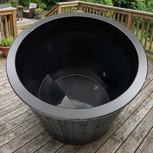The SaunaLife Model S1BC – 1-Person Immersion Tub with Black Chiller & Heater sits empty on a wooden deck, surrounded by greenery and patio furniture—a perfect outdoor home spa retreat from SaunaLife.