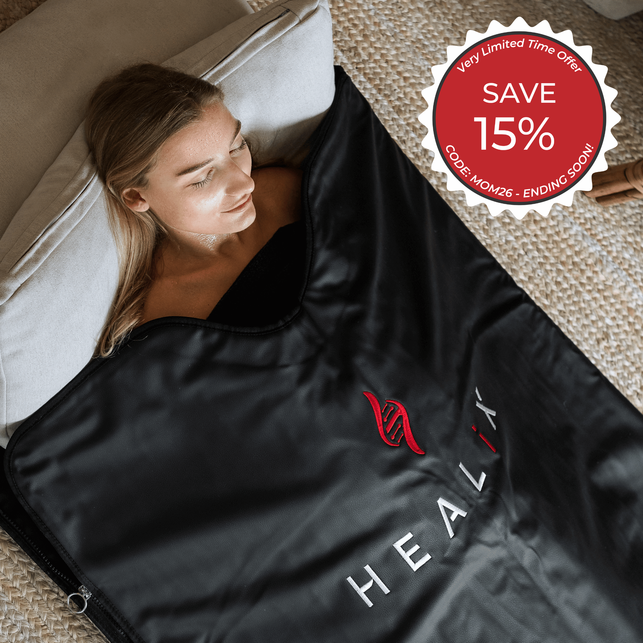 A woman relaxes on a cushion, wrapped in a HEALiX Infrared HEALiX-Z Sauna Blanket for an at-home spa experience. Red badge reads: Very Limited Time Offer—SAVE 15%, CODE: MOM26 - ENDING SOON!.