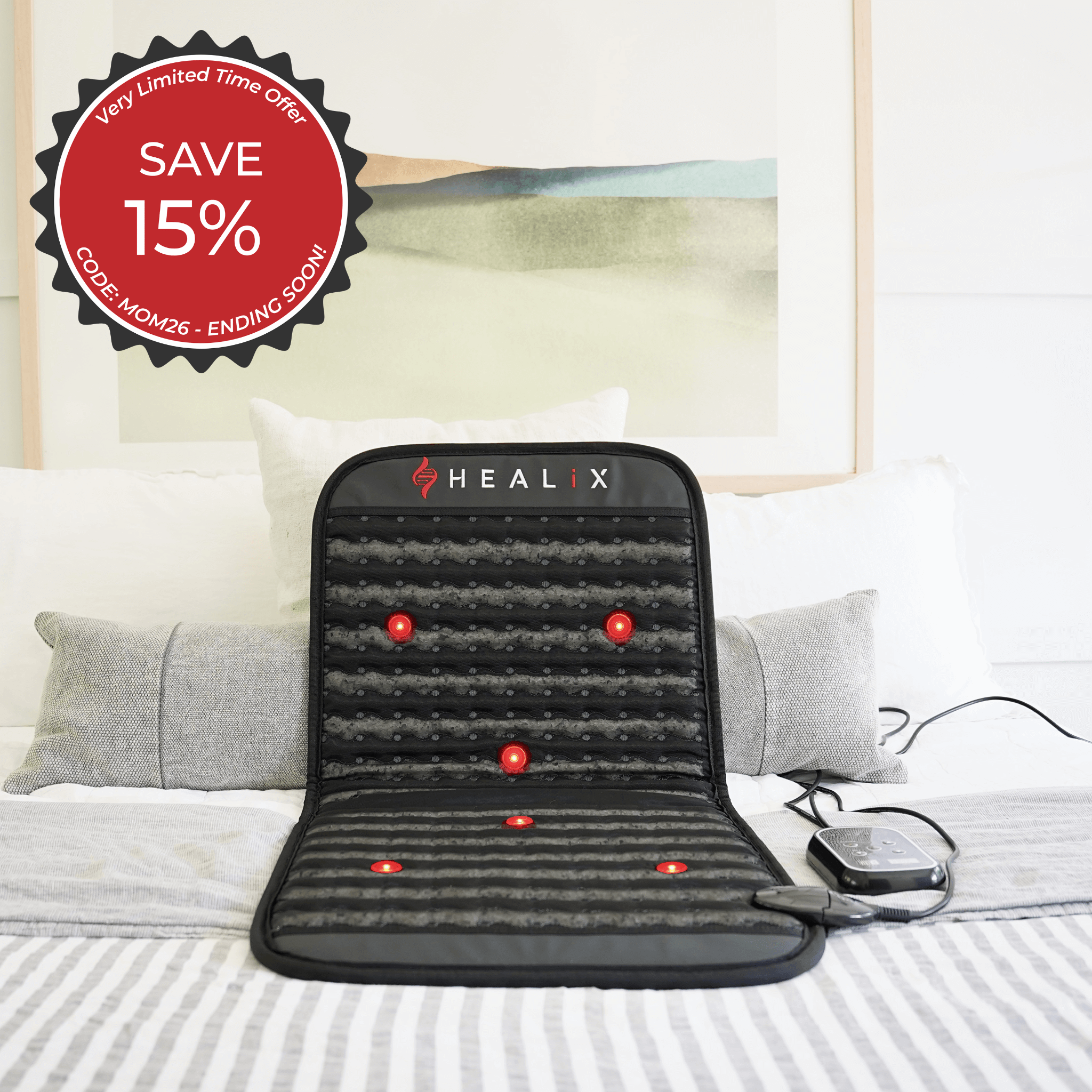 A HEALiX Revive Mini PEMF Mat by HEALiX Infrared with red indicator lights is placed on a bed, alongside its control device. A red badge in the top left advertises SAVE 15% with code MON26 for a limited time offer.