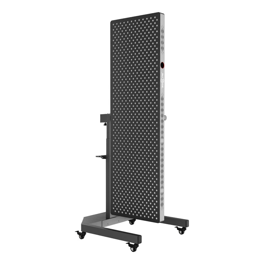 The RLT Home Total Spectrum ELITE (7 Wave 864 LEDs) is a tall, rectangular black metal red light therapy panel with a grid of circular holes, mounted vertically on a wheeled base for mobility and industrial use.