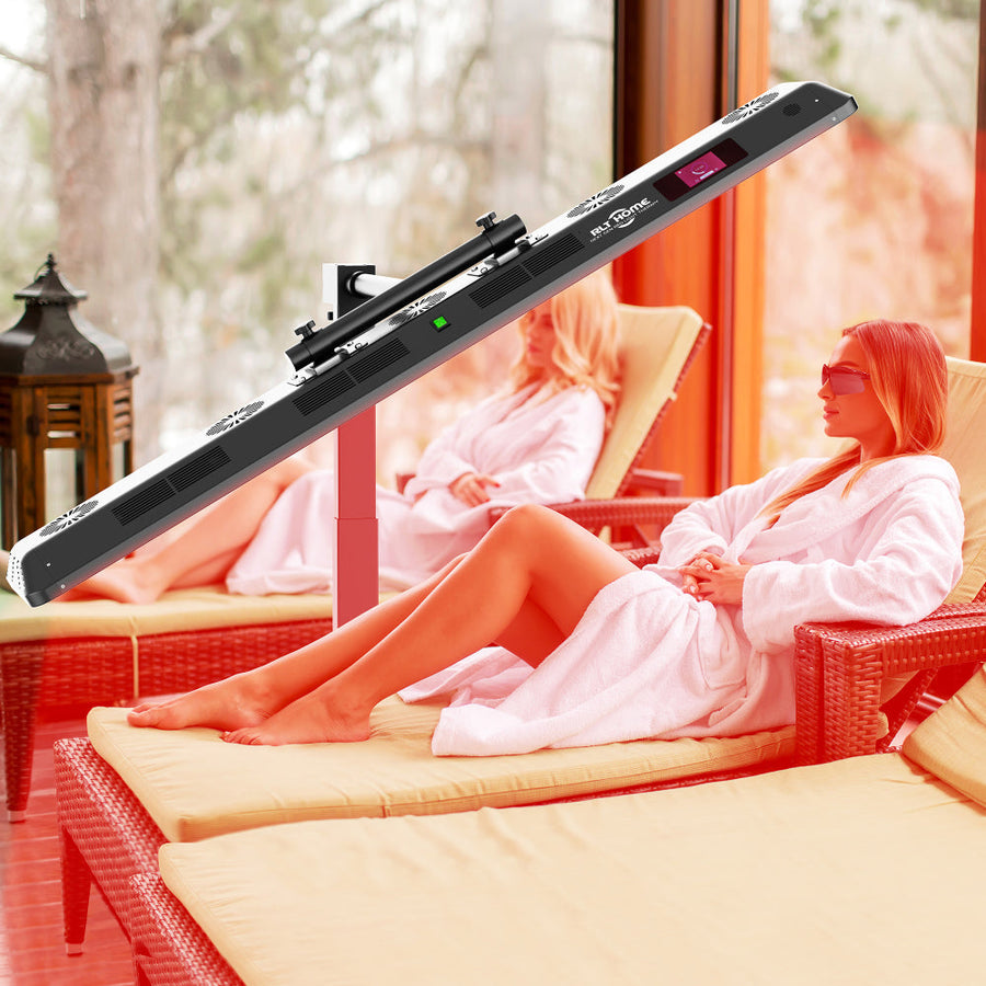 Two women in white robes relax on lounge chairs in a sunroom, enjoying the RLT Home Total Spectrum ULTRA Red Light Therapy Panel by RLT Home. Surrounded by windows and trees, they embrace full-body wellness and skin rejuvenation.