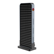 The RLT Home Total Spectrum COMPACT (7 Wave 216 LEDs) is a tall, rectangular red light therapy device with a grid of circular lights on the front and a small logo on the upper side edge, designed to aid pain recovery and support mitochondrial function.