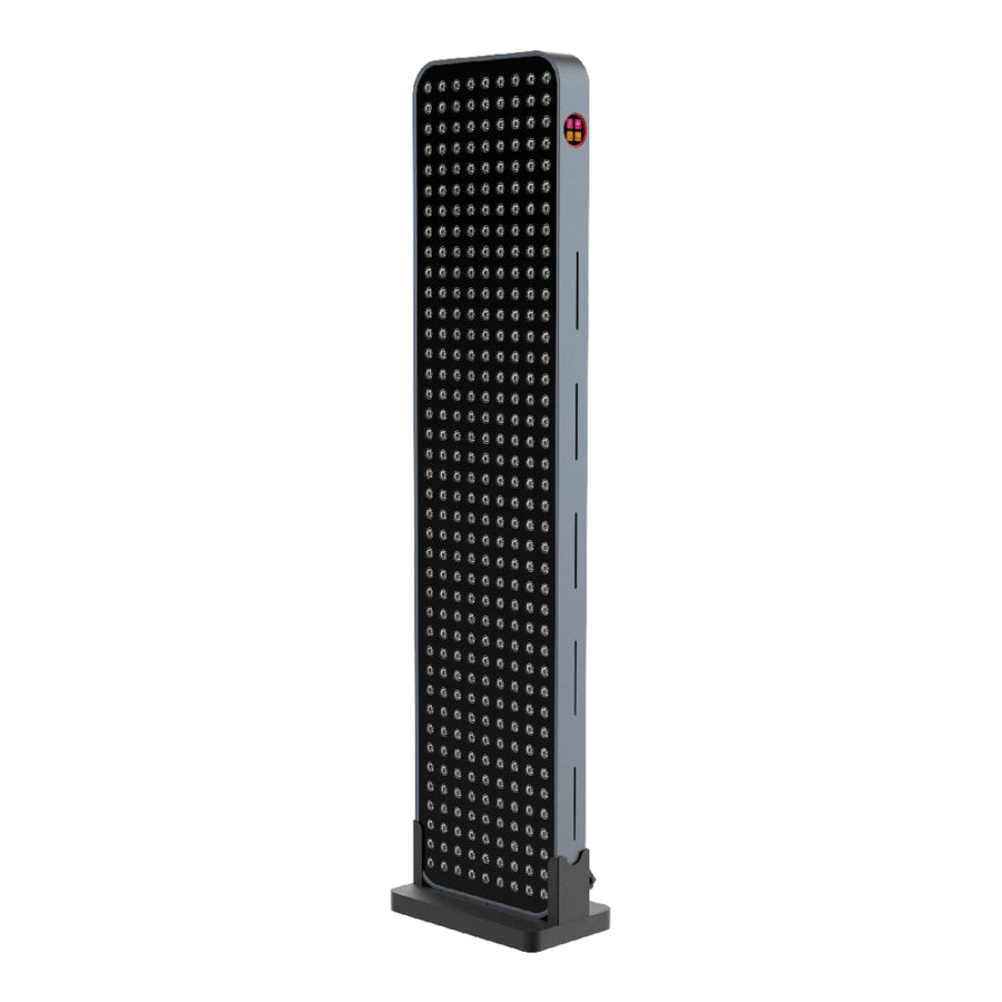 The RLT Home Total Spectrum MAX (7 Wave 360 LEDs) is a tall, rectangular red light therapy device with a black front grid of small round LEDs and a silver-gray frame, designed to stimulate mitochondria while standing upright on a flat base.