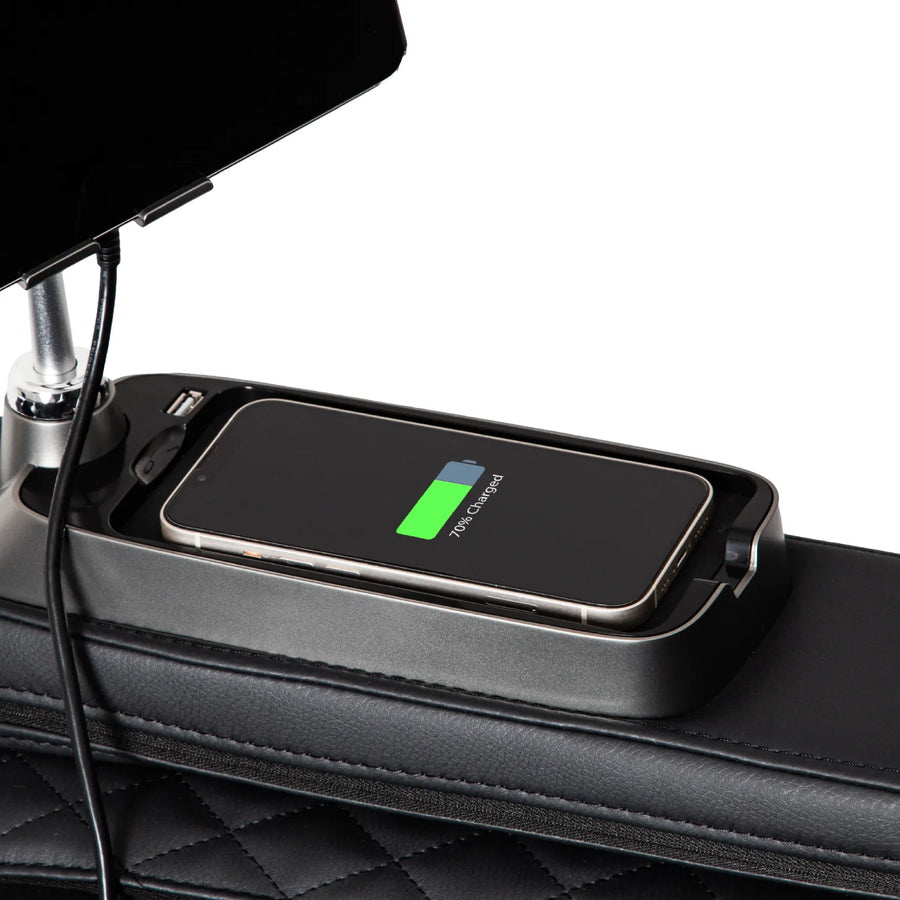 A smartphone charges wirelessly on a car armrest organizer featuring quilted black leather, echoing the premium upholstery of the Osaki 4D+3D Bravo Duo Flex massage chair. The phone’s charging symbol is visible, with a cable plugged into an adjacent holder.
