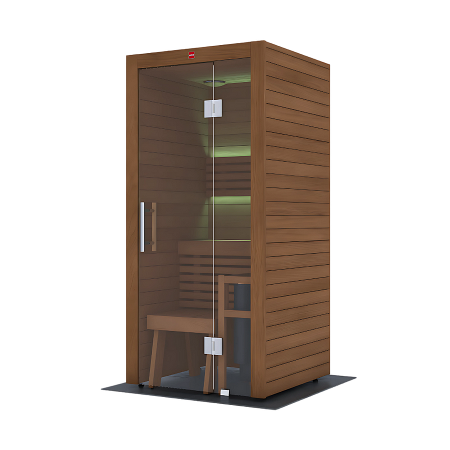 The LuxeWell Life Harvia Utu, a heat-treated 1-person indoor sauna, features Nordic spruce with horizontal slats, a glass door, wooden bench, and soft green LED lighting on the back wall. It stands on a dark mat against a plain white background.