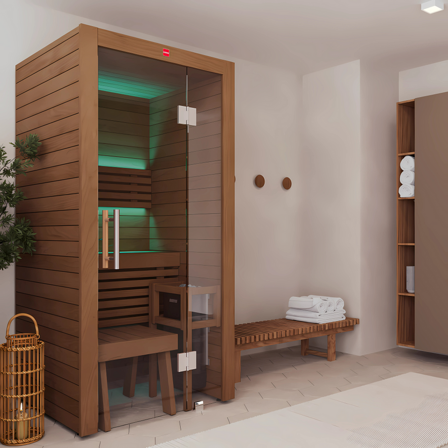 The LuxeWell Life Harvia Utu is a heat-treated, 1-person indoor sauna with Nordic spruce walls and a glass door, set in a minimalist space with wooden benches, shelves of rolled towels, wall hooks, and soothing green lighting inside.