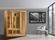 Maxxus Bellevue 3 person Low EMF FAR Infrared Sauna in a room with a white chair and a black and white forest photo.