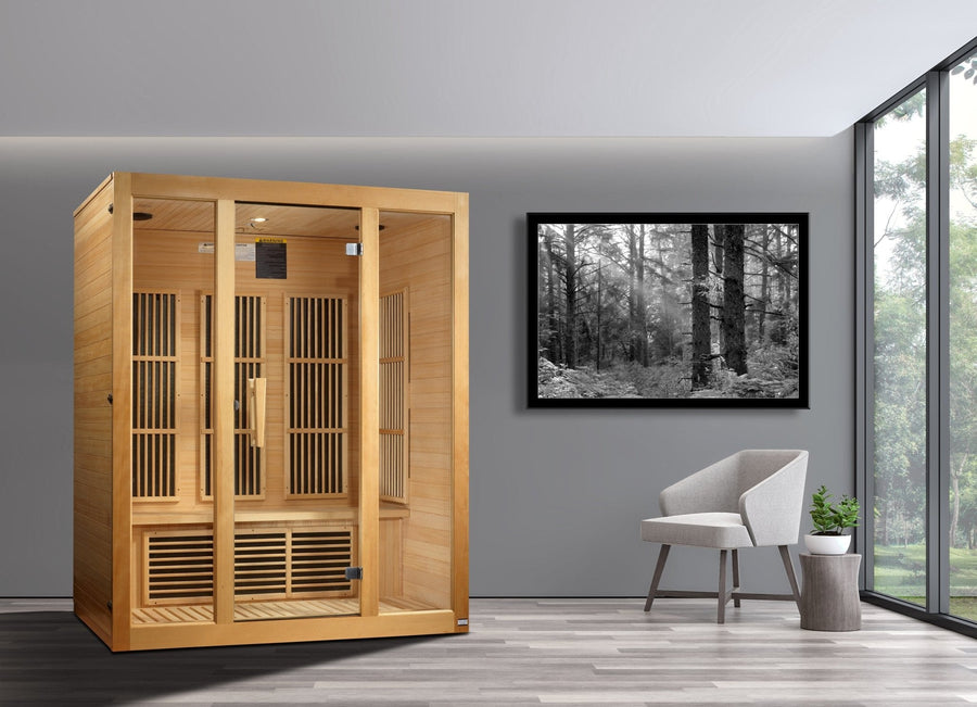 Maxxus Bellevue 3 person Low EMF FAR Infrared Sauna in a room with a white chair and a black and white forest photo.