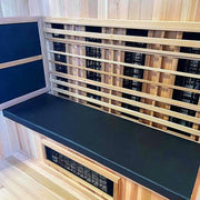 The Finnmark Sauna Cushion for FD-3, made from marine-grade vinyl, adds comfort and style to a modern wooden sauna interior with black bench seating—perfect for relaxing infrared therapy sessions.