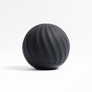 The VibePro Pulse by Icebound Essentials is a black, spherical vibration roller with a matte finish and spiral grooves, crafted for deep massage and effective muscle relief—displayed here on a white background.