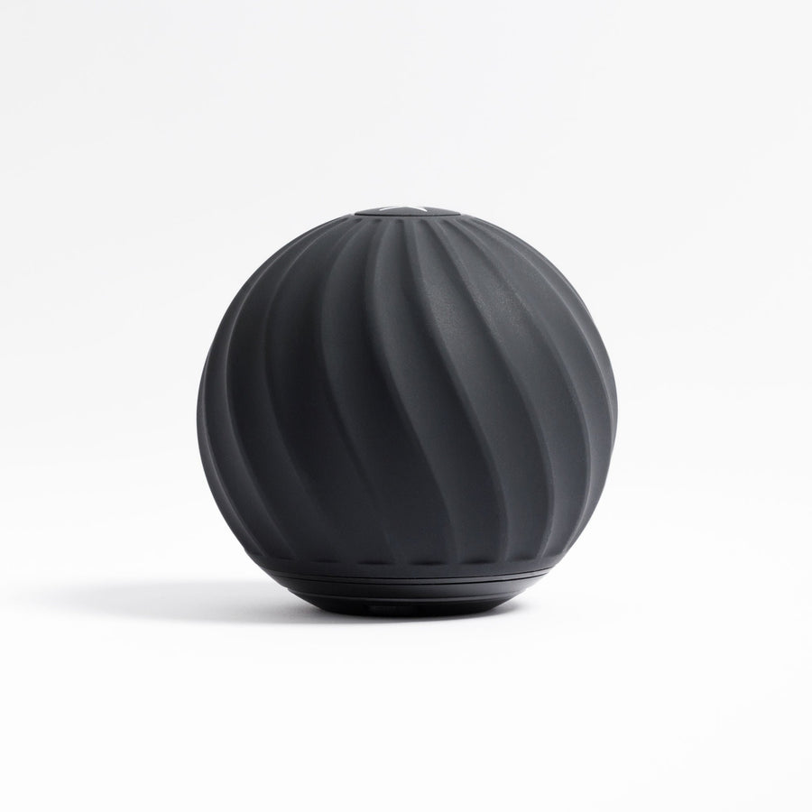 The VibePro Pulse by Icebound Essentials is a black, spherical vibration roller with a matte finish and spiral grooves, crafted for deep massage and effective muscle relief—displayed here on a white background.