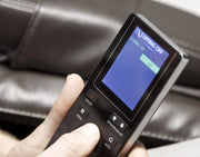 A hand holding the remote control for the Daiwa Legacy 4 Massage Chair, showcasing its advanced features and modern design.