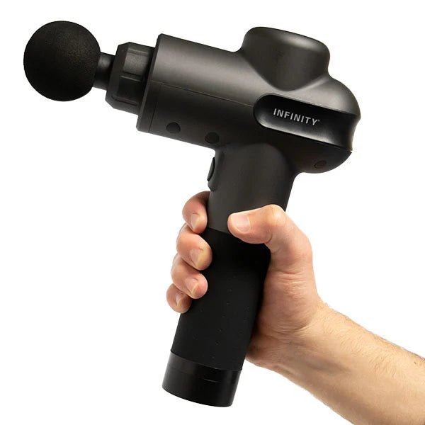 A hand holding the Infinity PR Pro Endurance Percussion Massage Device, showcasing its ergonomic design and portable size.