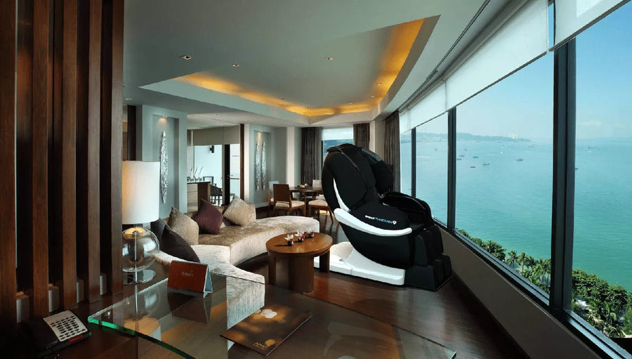 Medical Breakthrough 9 massage chair in a room with ocean view, round wooden table with flowers, and a couch with pillows.